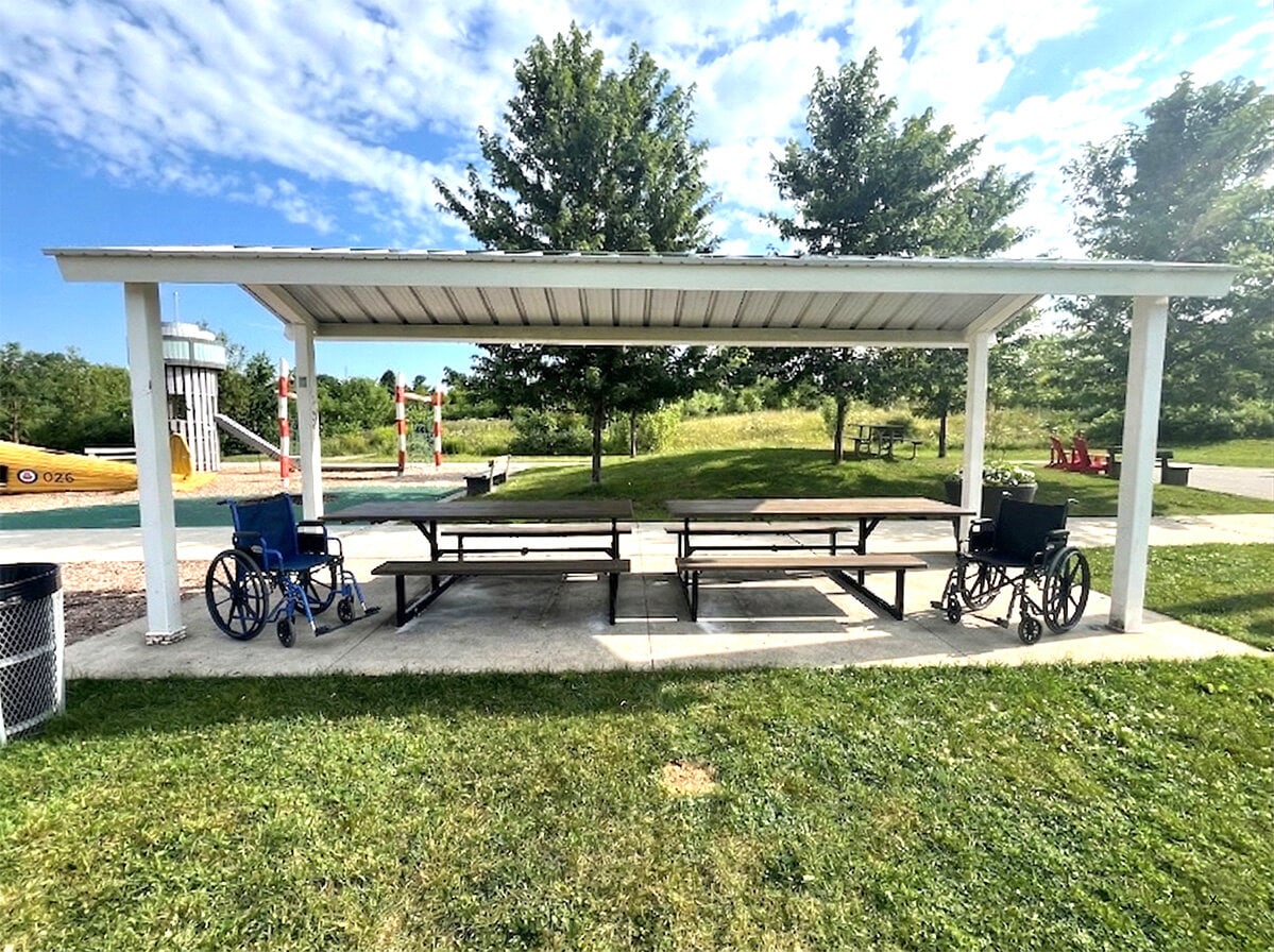 Accessible commercial picnic tables under a park shelter with wheelchair access spaces, designed for inclusive outdoor seating in public parks and community spaces